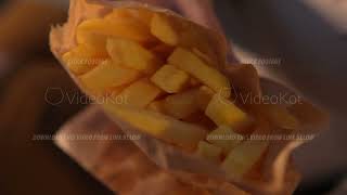 Macro footage of appetizing french fries wrapped in paper in female hands filmed from above [upl. by Leahcimaj]